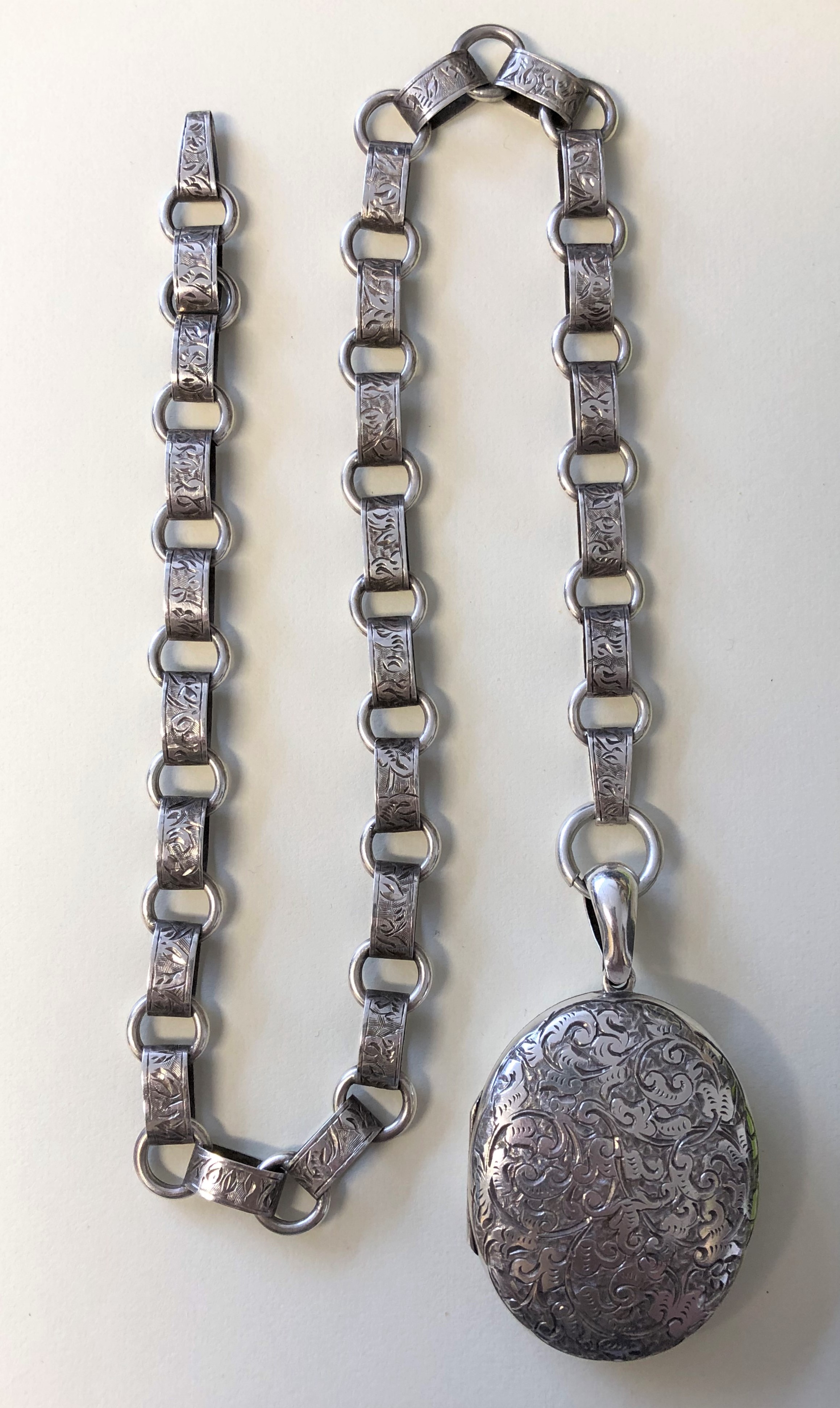 SILVER OVAL ENGRAVED LOCKET ON A SILVER ENGRAVED LINK CHAIN 38.