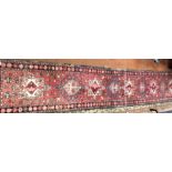 CAUCASIAN CARPET RUNNER WITH NINE MEDALLION CENTRAL RESERVED ON A RED GROUND 53CM X 315CM APPROX