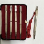 CASED SET OF FOUR STERLING SILVER AND ENAMEL CARD SUIT PROPELLING PENCILS AND A SILVER MINIATURE