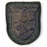 A Third Reich Krim shield, of bronzed iron on field grey cloth patch, with original paper backing