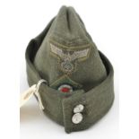 A Third Reich olive green field cap, with woven silver eagle and cockade, the lining with traces