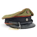 A WWI style Prussian officer’s peaked cap, of pale grey/green fabric with black band and red