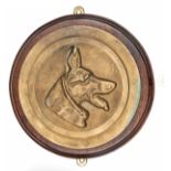 A cast brass circular badge of HM tug Alsatian, showing an alsatian’s head sideways in plain