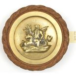 A small cast brass tompion badge of HMS Neptune, battleship 1909-22, showing the sea god holding