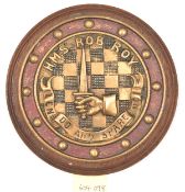 A cast brass circular badge of HMS Rob Roy, destroyer 1916-26, showing crest of hand holding upright