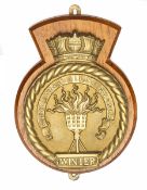 A cast brass badge of HMS Winter, showing a burning brazier and scroll “Winter freezeth not our