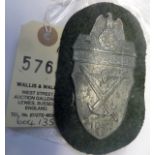 A Third Reich Demjansk arm shield, of zinc on field grey cloth patch with backing plate. GC