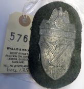 A Third Reich Demjansk arm shield, of zinc on field grey cloth patch with backing plate. GC