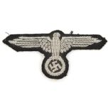 A good Third Reich SS officer’s embroidered arm eagle, alloy braid, still retains some paper