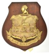 A cast brass badge of HMS Sir John Moore, monitor 1915-21 showing an ornamental shield with 2