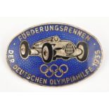 A Third Reich pin back oval enamelled badge, depicting a racing car (Mercedes?) above the Olympic