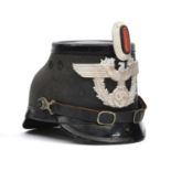 A Third Reich Berlin police shako, of black fibre with patent leather trim, aluminium eagle badge