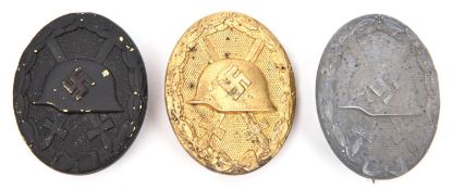 Three Third Reich wound badges: gold with solid back and "L/14" maker's code; grey metal with