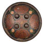 An Indian lacquered shield dhal. c.1900, 34.5cms, with 4 large iron bosses, surface with 4 gilt