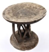An African wooden stool, carved from a section of tree trunk, with shallow cup shaped top and