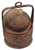 An African raffia woven circular basket, domed lid, stripwood carrying handle with central ring,