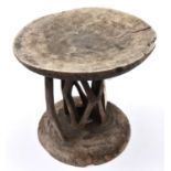 An African wooden stool, carved from a section of tree trunk, with shallow cup shaped top and