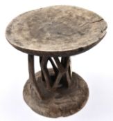 An African wooden stool, carved from a section of tree trunk, with shallow cup shaped top and