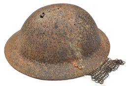 A British WWI Brodie steel helmet, in heavily corroded excavated condition, with wire rail and