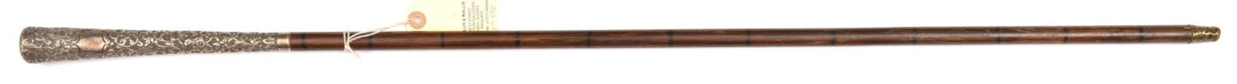 An imitation dark bamboo walking cane, the haft with painted rings, long flared Eastern silver grip,