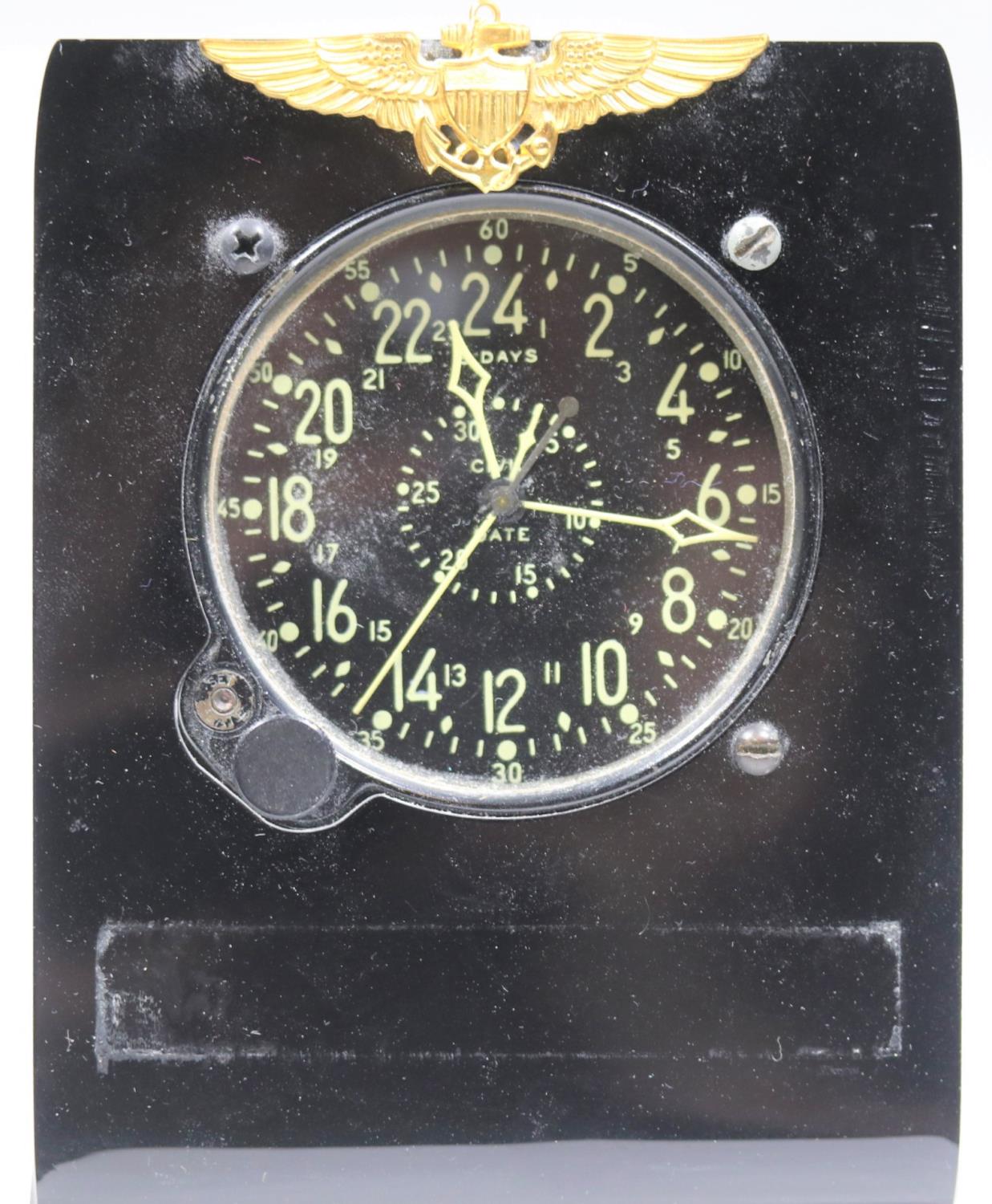 Waltham cockpit clock. Bakelite and aluminium housing with plastic stand. USN wings afixed to stand.