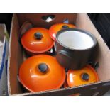 A box containing Le Creuset pans, tray and covers