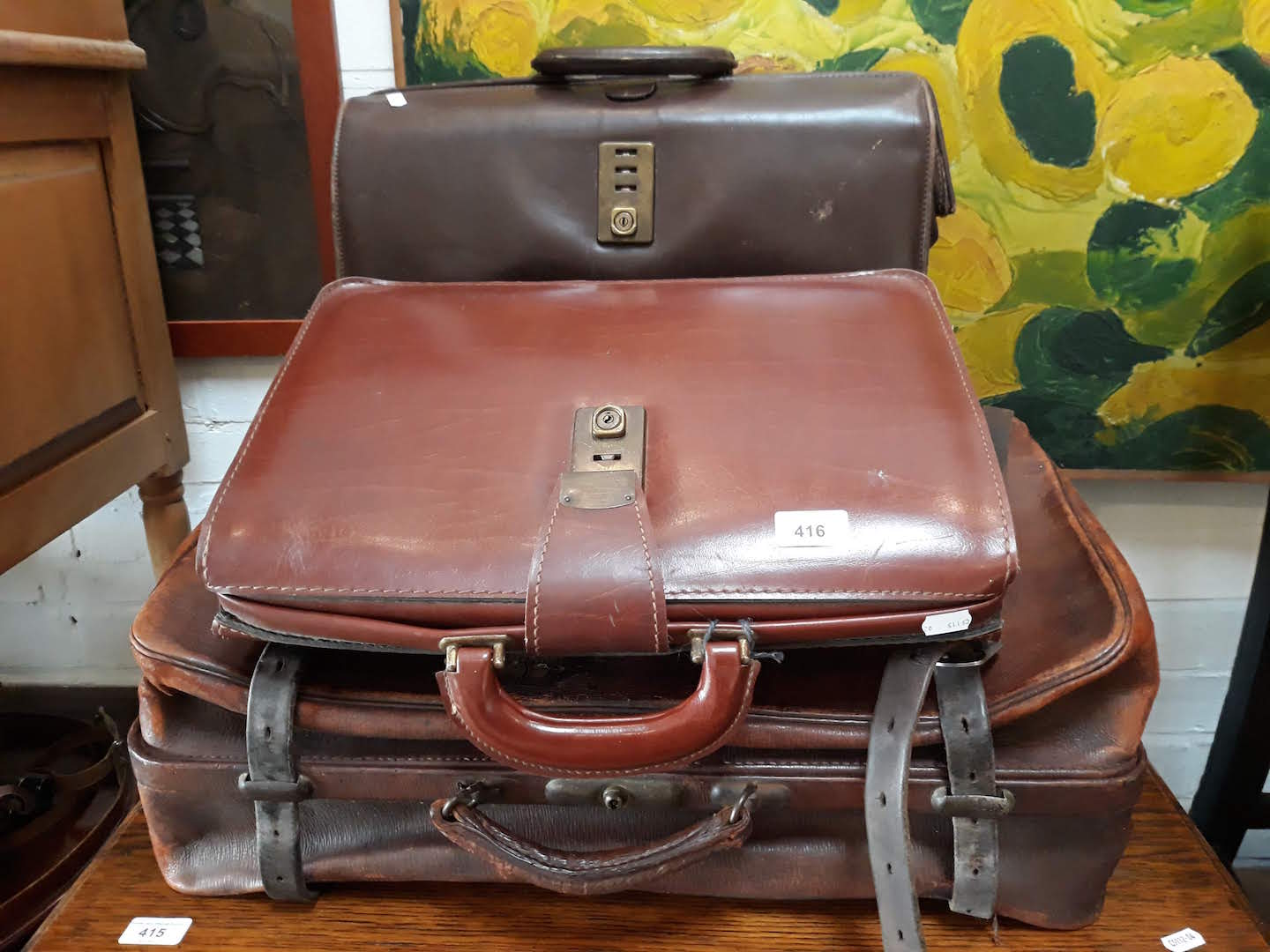 Three brown leather vintage suitcases.