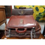 Three brown leather vintage suitcases.