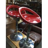 A pair of red metal bar stools