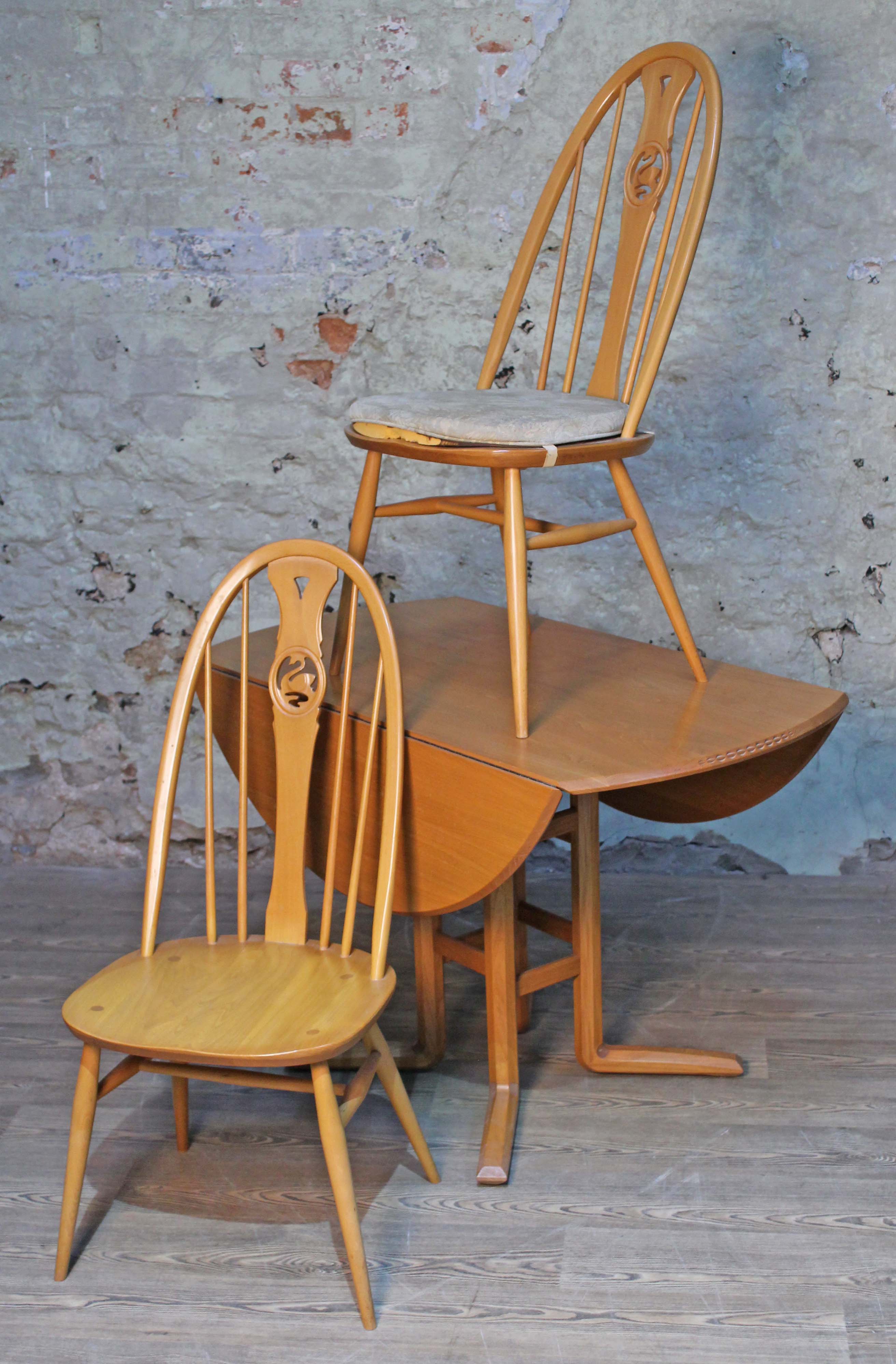 An Ercol blonde elm and beech Campden 955 drop leaf table and two swan back chairs.