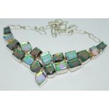 A silver necklace set with purple/green coloured gems.