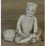 A Japanese bone okimono depicting a man chopping vegetables, height 11.5cm.