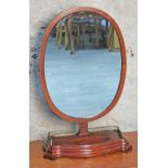 An Edwardian mahogany oval toilet mirror with lower pierced brass gallery rail, height 73cm.