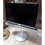A Bang & Olufsen Beovision 7 TV with Beo4 remote, stand and soundbar.