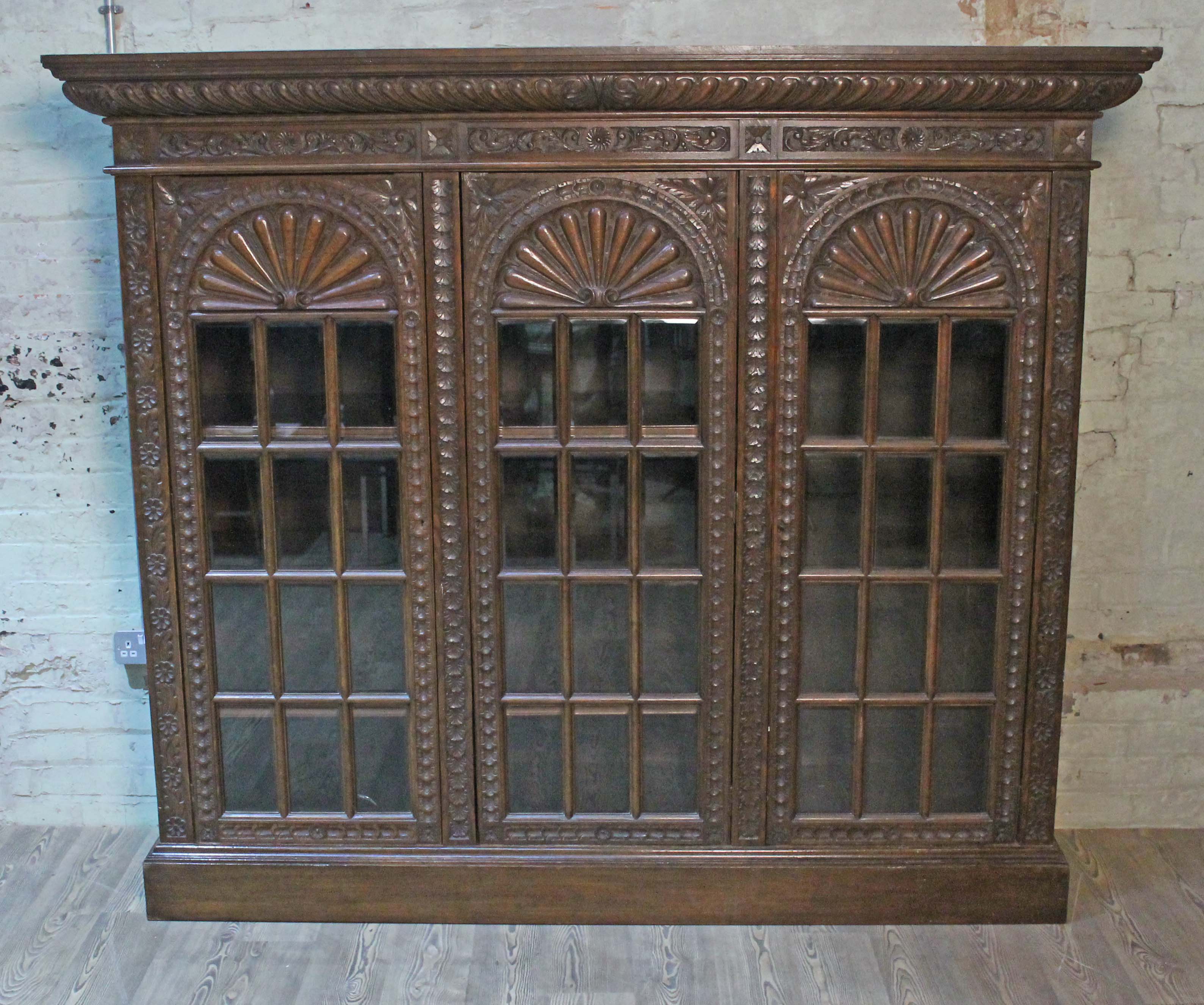 A late Victorian large carved oak glazed bookcase having gadrooned cornice, acanthus frieze,