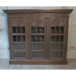 A late Victorian large carved oak glazed bookcase having gadrooned cornice, acanthus frieze,
