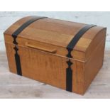 An Arts & Crafts light oak sewing box of domed casket form with black metal strap work and visible