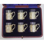 A cased set of six silver liquor tots with continental style decoration and glass liners, James