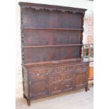 An oak dresser circa 1900 with plate rack back, geometric drawer fronts and brass handles,