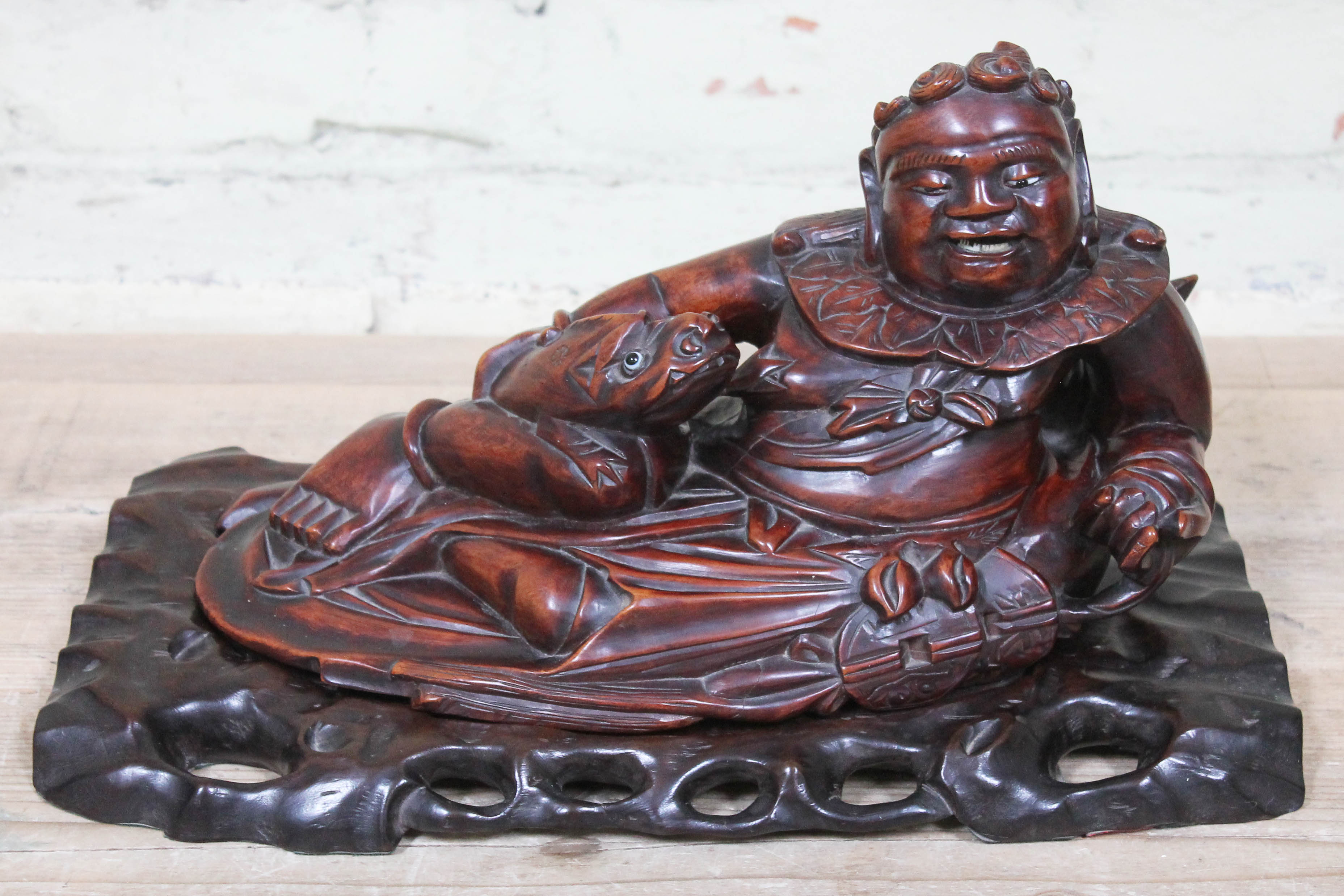 A Chinese carved hardwood figure depicting a seated man with fish on base, length 40cm.