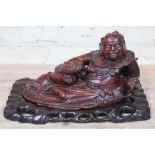 A Chinese carved hardwood figure depicting a seated man with fish on base, length 40cm.