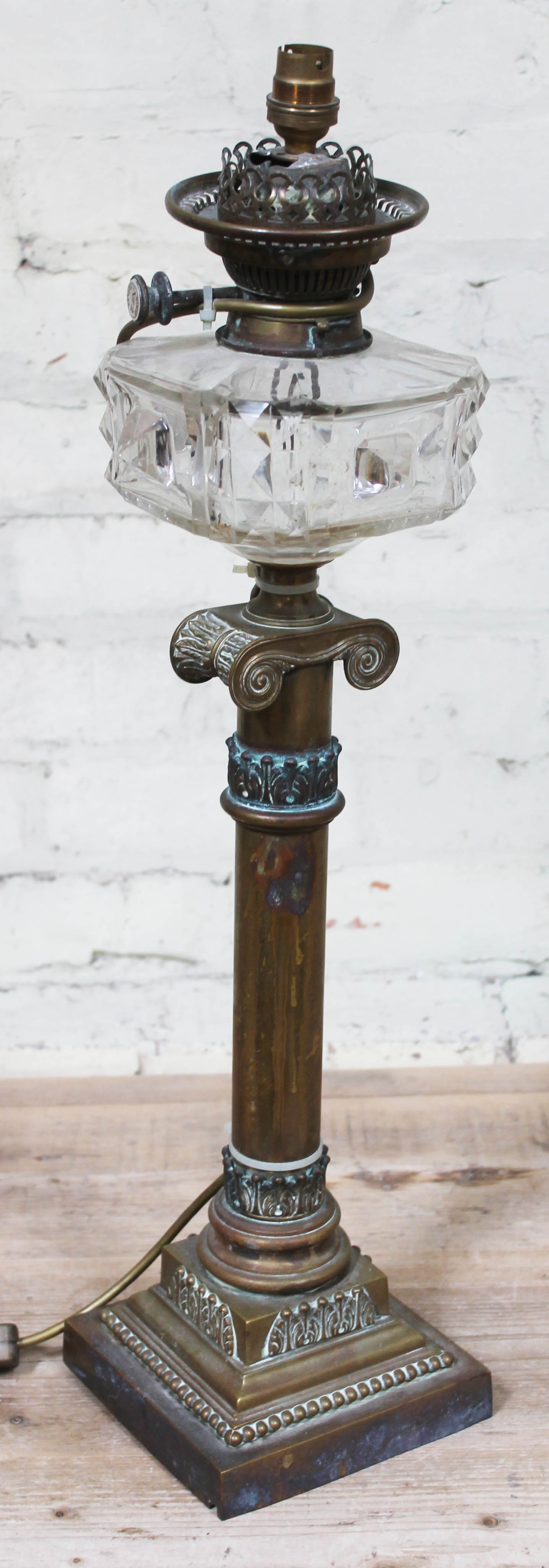 A Victorian brass lamp with cut glass reservoir, single column with acanthus mouldings and ionic