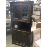 An oak corner cabinet with leaded glass