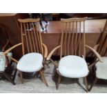 A pair of Ercol blonde spindle back armchairs.