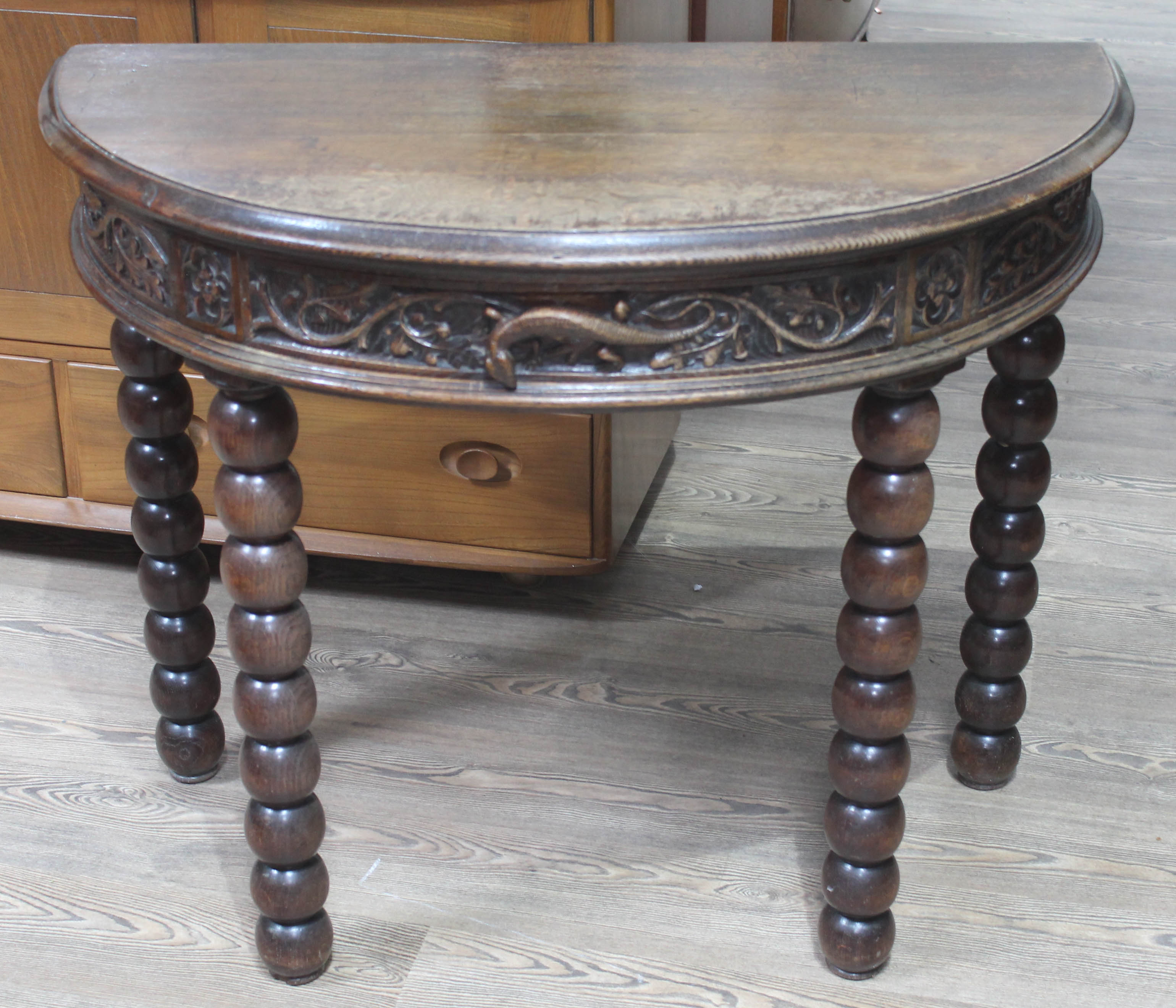 A Victorian demi-lune oak console table, the frieze and drawer carved with leaves, Gothic style