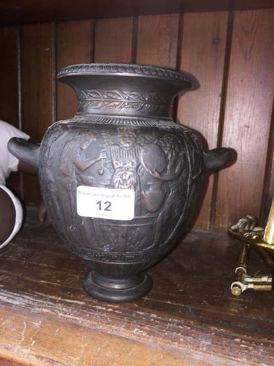 A cast iron urn with handles depicting Greek figures.