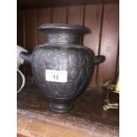 A cast iron urn with handles depicting Greek figures.