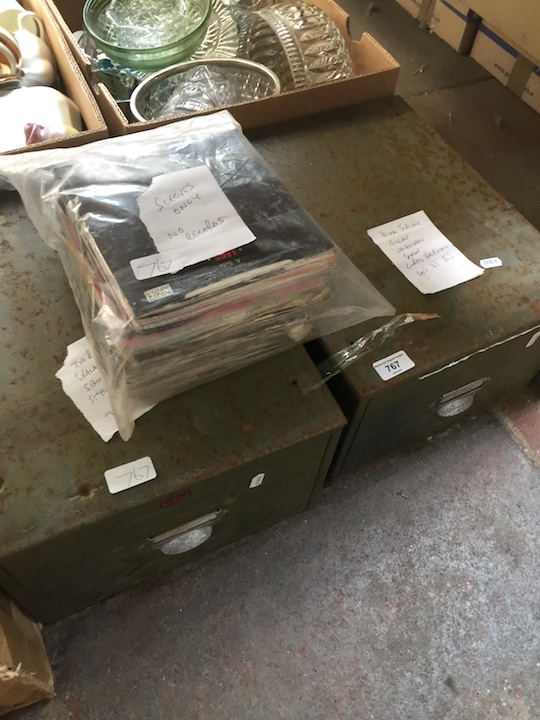 Two metal drawers of single 45 records and a bag of empty record sleeves.