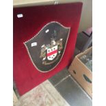 A leather heraldic shield on velvet backboard