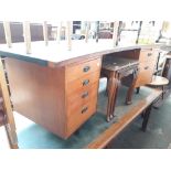 A vintage teak desk with tooled leather top